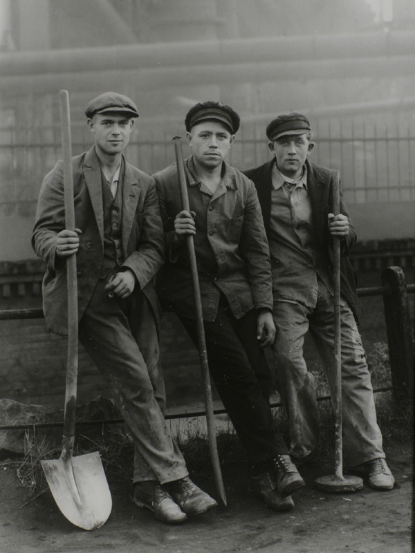Workers from the late 19th century wear tailored jackets, waistcoats, peaked caps and heavy-duty boots, a look that is often imitated today.