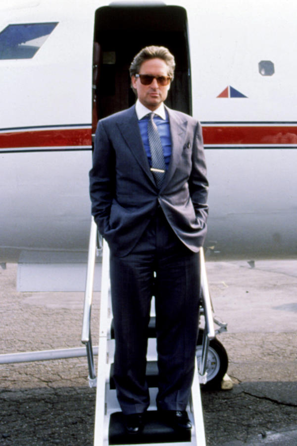 Sporting another blue shirt with a white contrast collar shirt this time under a grey single-breasted suit, Gekko accessorises with a tie, silver tie bar, pocket square and pair of Ray-Ban wayfarer sunglasses. Photograph by 20th Century Fox Film Corp/ Everett/Alamy.