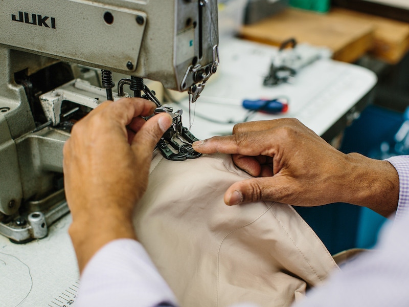 A craftsman sewing on a button which then gets scrupulously checked by Rima, Grenfell's quality control officer. Photo by Jamie Ferguson.