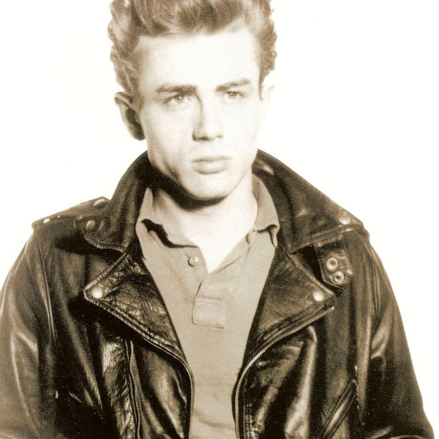 James Dean favoured leather jackets as part of his off-duty attire, pictured here wearing a black version over a polo shirt, circa 1954.