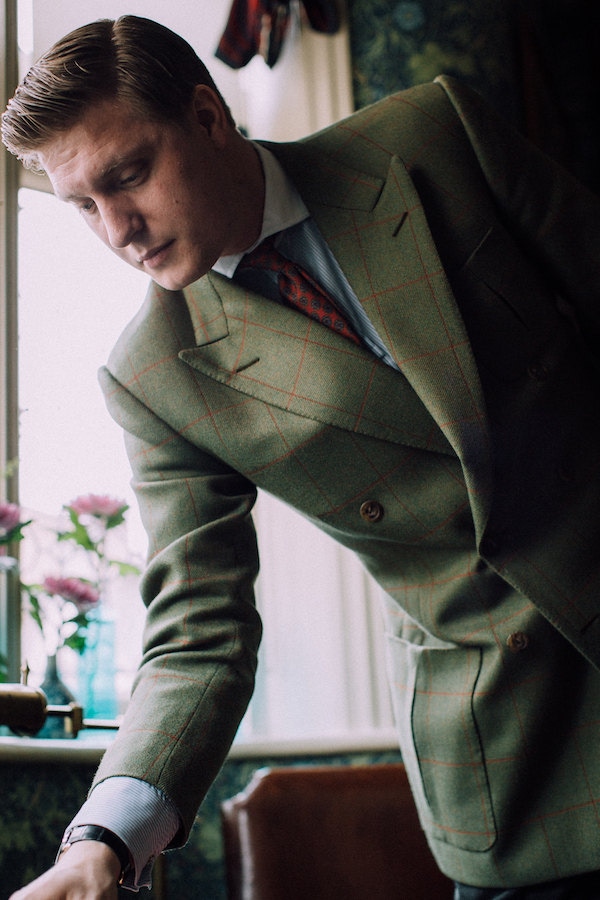 Tom is a loyal patron of Kent, Haste & Lachter, having been introduced to the tailoring house by menswear expert Nick Foulkes. His double-breasted sports coat is cut in an olive green Bateman Ogden tweed with an overcheck that, at first sight, appears red, but on closer inspection has lovely flecks of pink, orange and gold woven through. The inverted box pleat pockets and a half-belt in the back are personal touches Tom requested.