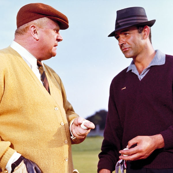 James Bond, wearing a Slazenger V-Neck, goes head-to-head with Goldfinger during a round of golf.