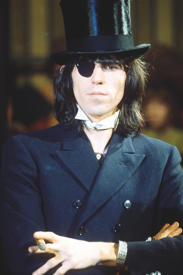 Performing at The Rolling Stones Rock and Roll Circus wearing a double-breasted peaked lapel jacket, detachable wing-tip collar, eye-patch and top hat, 1968. Photograph by REX/Shutterstock.