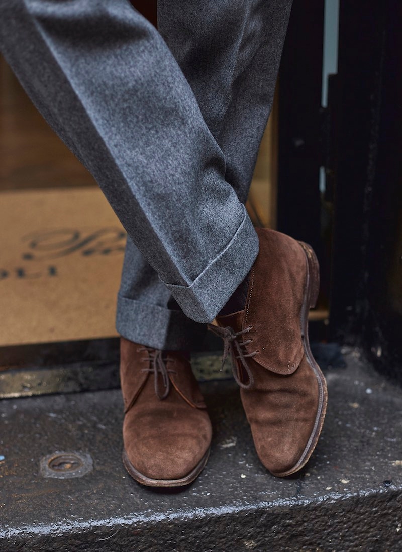 With his grey flannel suit he spots a pair of chukka boots.