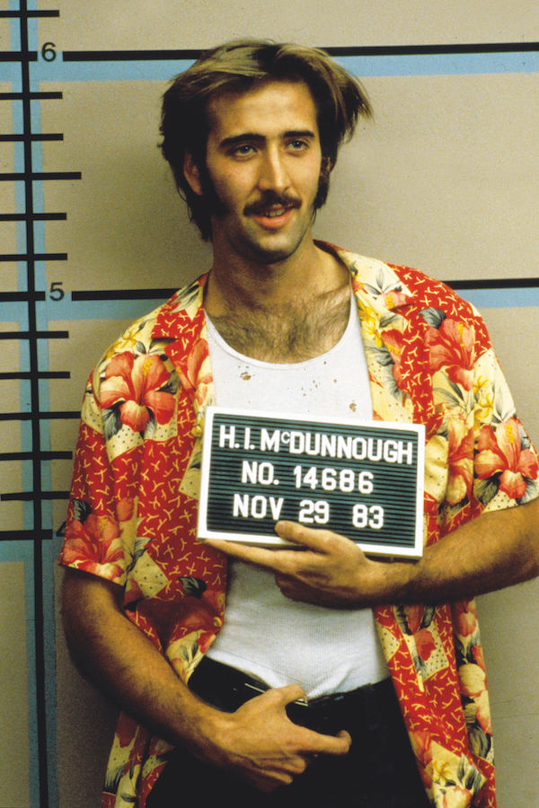 Nicolas Cage demonstrates a casual approach wearing his shirt open with a white vest shirt underneath in Raising Arizona, 1987. Photograph by Moviestore/REX/Shutterstock