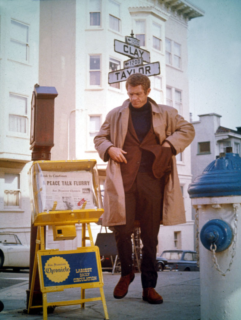 Sporting a navy rollneck beneath a tweed jacket and raincoat in Bullitt, 1968.