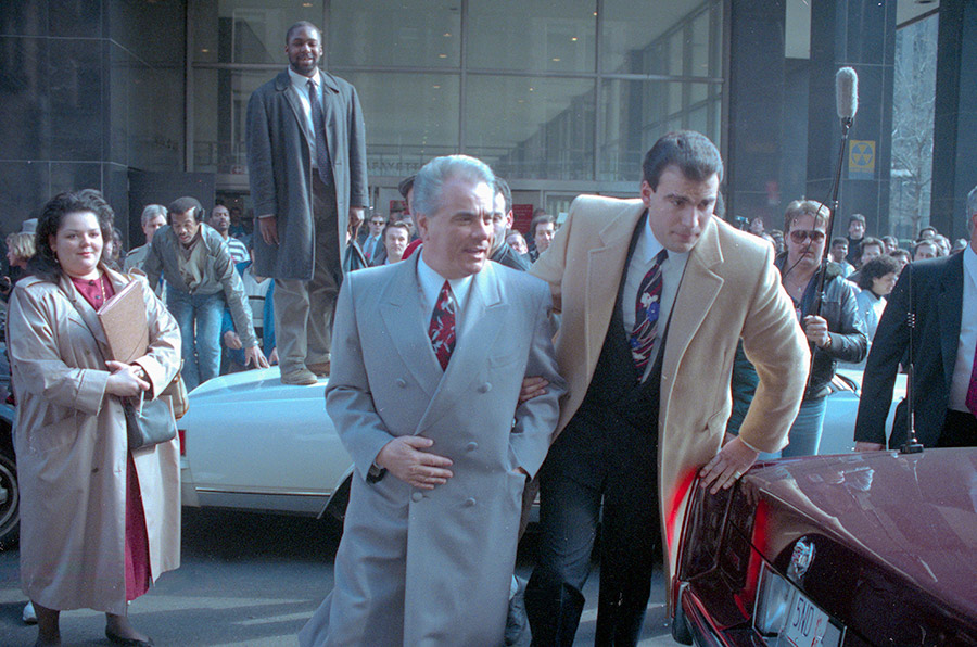 Gotti in a beautiful double-breasted overcoat - note the small tie knot and narrow spread collar, the Don's signature look (Getty).