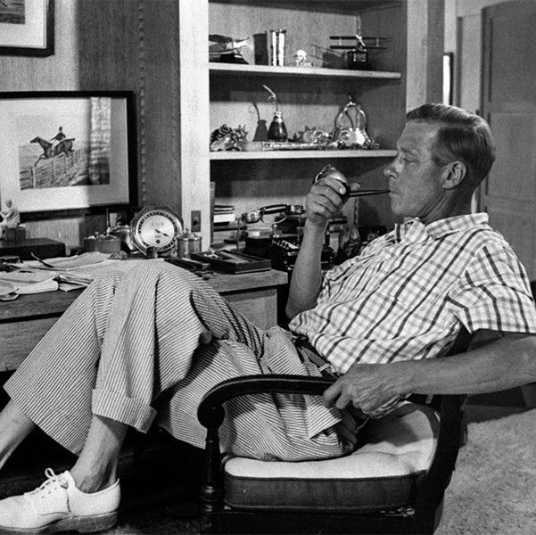 The Duke of Windsor relaxes and has a smoke in a pair of seersucker trousers with a turn-up, worn sans socks with a pair of white derbies.