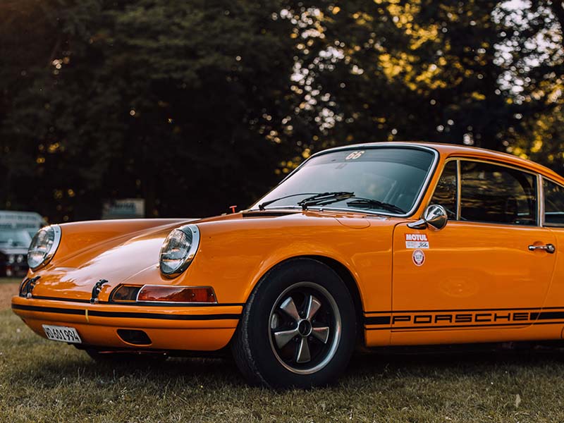 An orange Porsche 911 with racing decals.