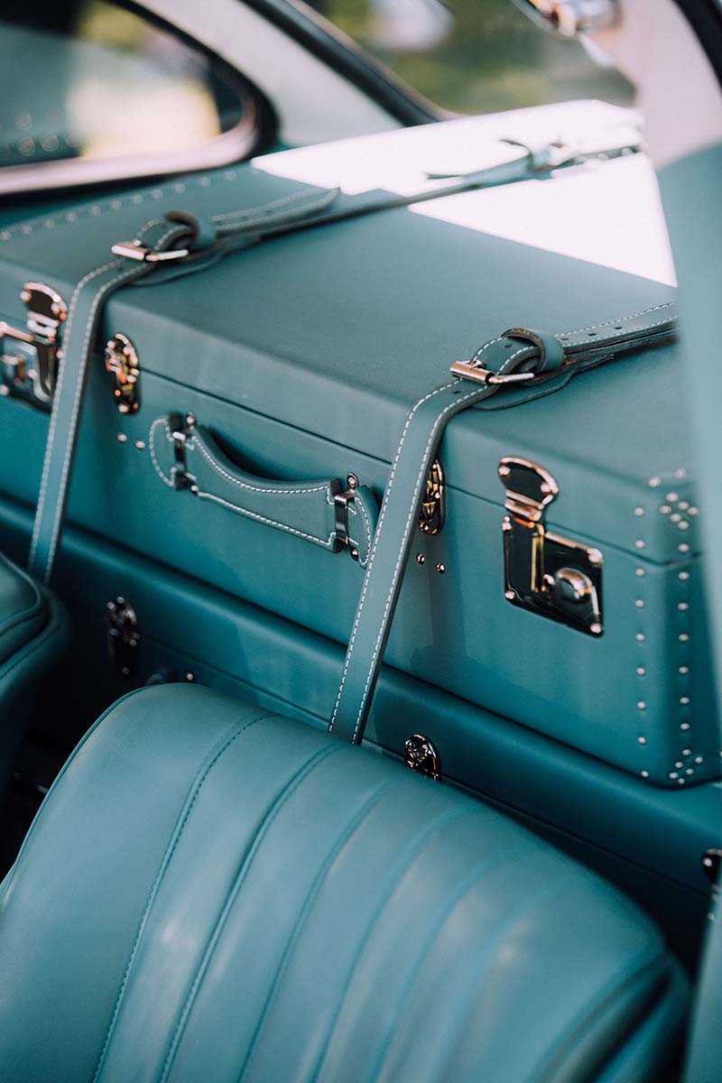 The sleek, monochromatic blue interior of a classic car with luxury matching luggage from Globe Trotter.