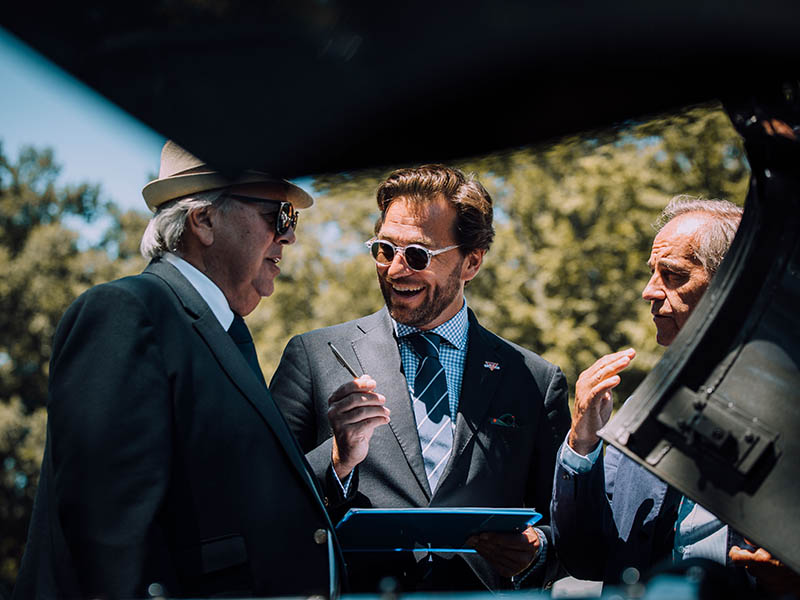 Stylish motorists converse with Frédéric Brun whilst inspecting a classic car.