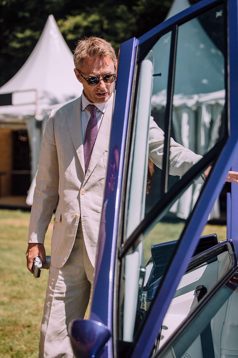 Simon Kidston wears an ecru suit with a purple tie, white shirt and sunglasses.