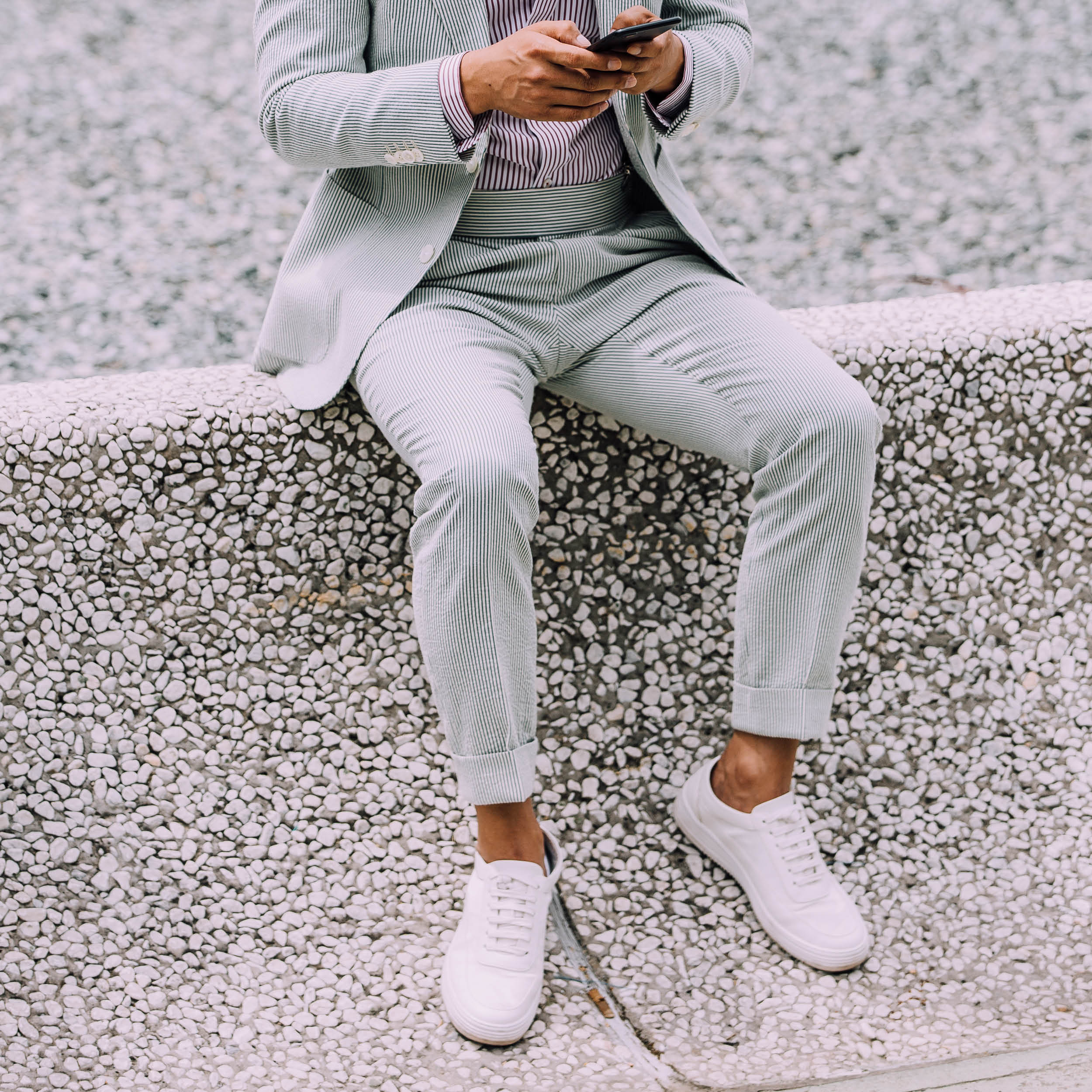 A pastel blue suit and striped shirt paired with minimalist white sneakers. A crisp white pocket square co-ordinates perfectly with the white trainers.