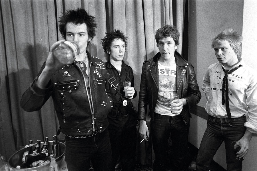 Celebrating with Johnny Rotten, Steve Jones and Paul Cook after signing a record deal, 1977. Photograph by Rex Features.