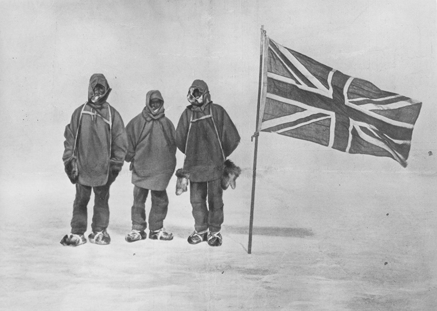 Circa 1909: Irish explorer Sir Ernest Henry Shackleton and two members of his expedition team beside a Union Jack within 111 miles of the South Pole, a record feat. (Photo by Hulton Archive/Getty Images)