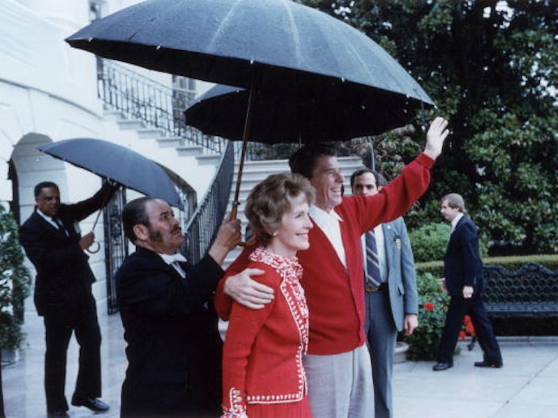 US President Ronald Reagan under an umbrella with First Lady Nancy Reagan after leaving George Washington Hospital, Washington, DC (Photo by Ronald Reagan Library/Getty Images).