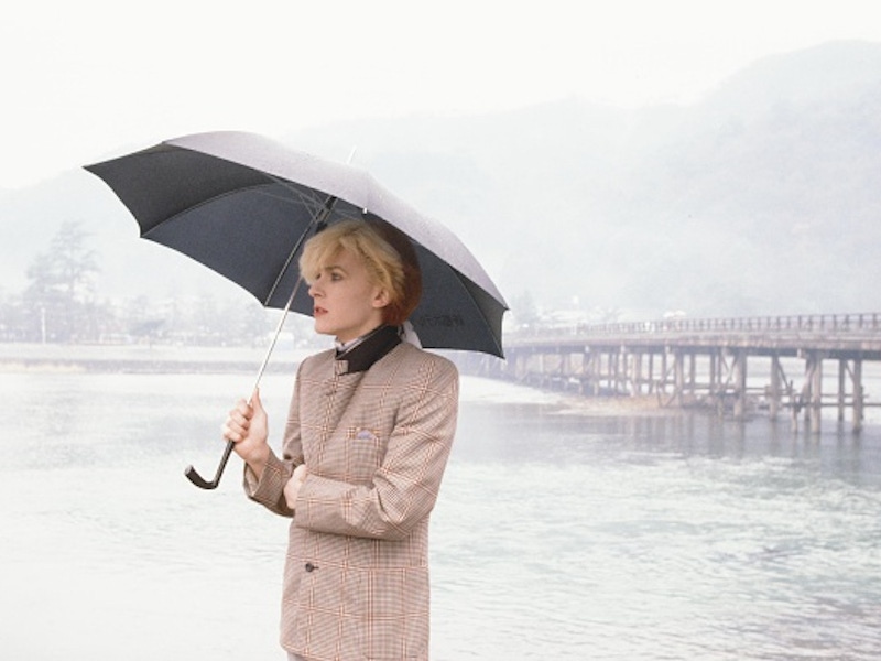 David Sylvian an English singer-songwriter standing with umbrella at the riverside in rainy Arashiyama Kyoto, Kyoto, February 1981 (Photo by Koh Hasebe/Shinko Music/Getty Images).