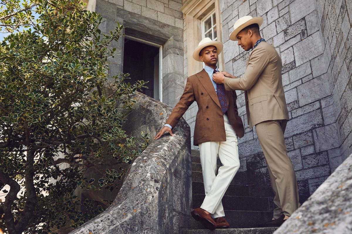 Solomon: Brown linen double- breasted jacket, Rubinacci at The Rake; blue linen buttondown shirt, 100 Hands at The Rake; burgundy Paisley silk Madder tie, Budd Shirtmakers; cream wool trousers, G. Inglese at The Rake; classic Panama Hat, Lock & Co; tan Polo suede Gabriel tassel loafer, George Cleverley. Kidane: Tan wool double-breasted suit, Gaiola at The Rake; indigo block print short-sleeve shirt, Kevin Seah; wide brim Panama hat, Lock & Co; brown mink suede Islington shoe, Edward Green.