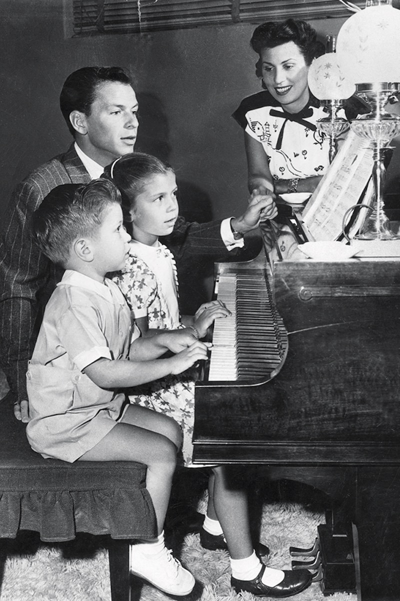 Sitting at the piano with his first wife, Nancy Barbato, and their children, Nancy and Frank Jr. (Photo by Hulton Archive/Getty Images)