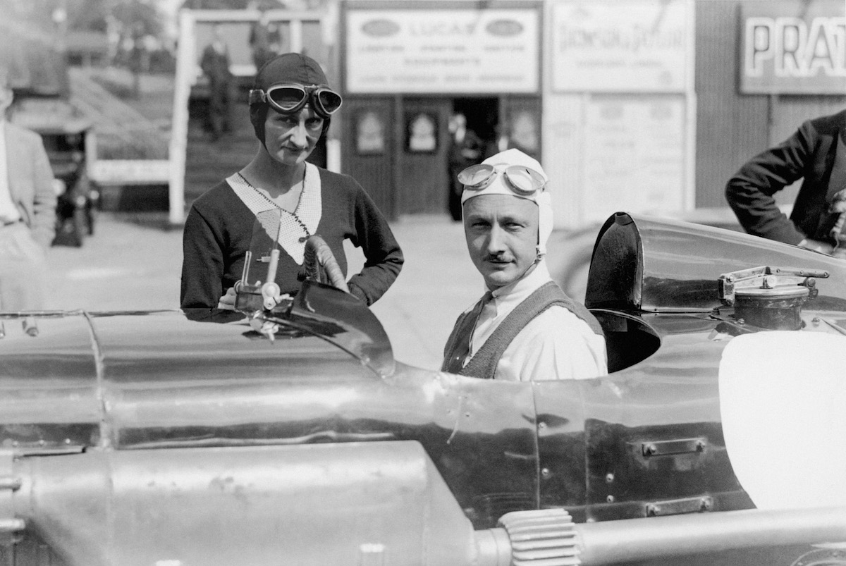 Sir Henry Birkin sits in his Blower Bentley and talks with Mrs Elsie Wisdom. Photo by Barratts/PA Images via Getty Images.