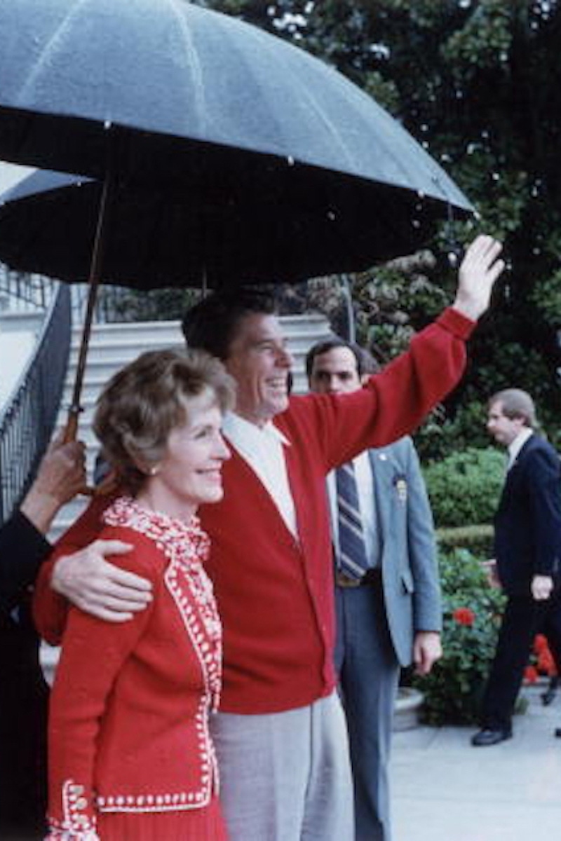 Ronald Reagan smiles and waves as he stands under an umbrella with First Lady Nancy Reagan after leaving George Washington Hospital, Washington, DC. (Photo by Ronald Reagan Library/Getty Images)