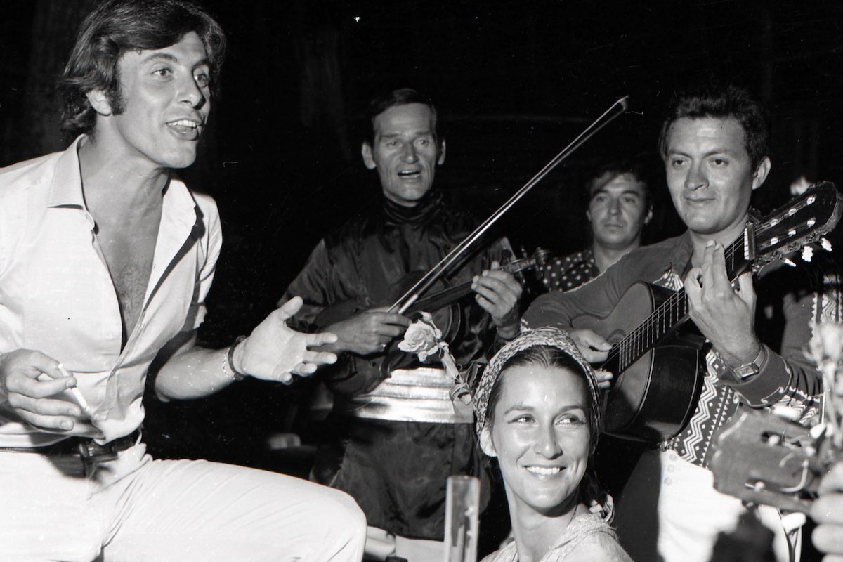 Rizzi, in a signature open-neck shirt, alongside a band of musicians in 1968