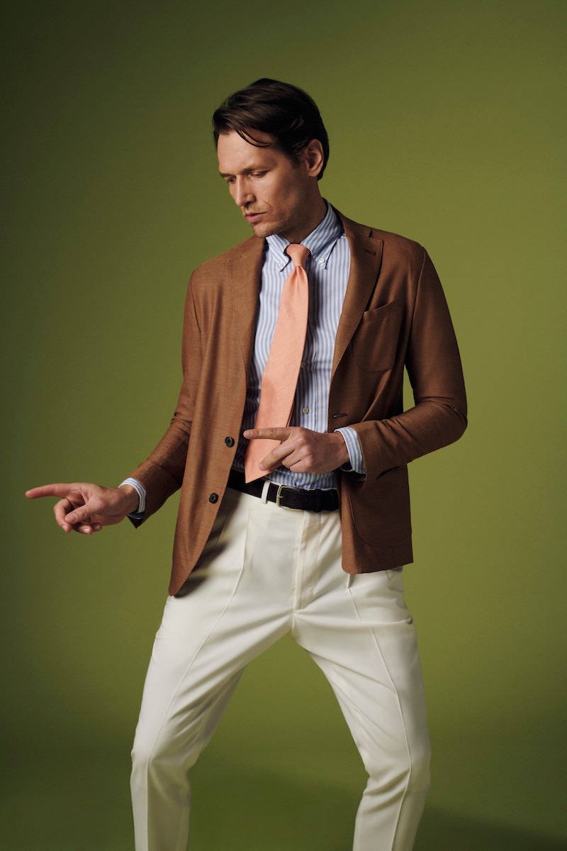 Terracotta wool unlined single-breasted patch pocket jacket, Sacco; light blue striped royal Oxford shirt, Eton; orange silk-linen Ibiza tie with pinstripes, Calabrese 1924; Off white wool gabardine pleated trousers, The Rake Tailored Garments; brown suede belt, Elliot Rhodes.