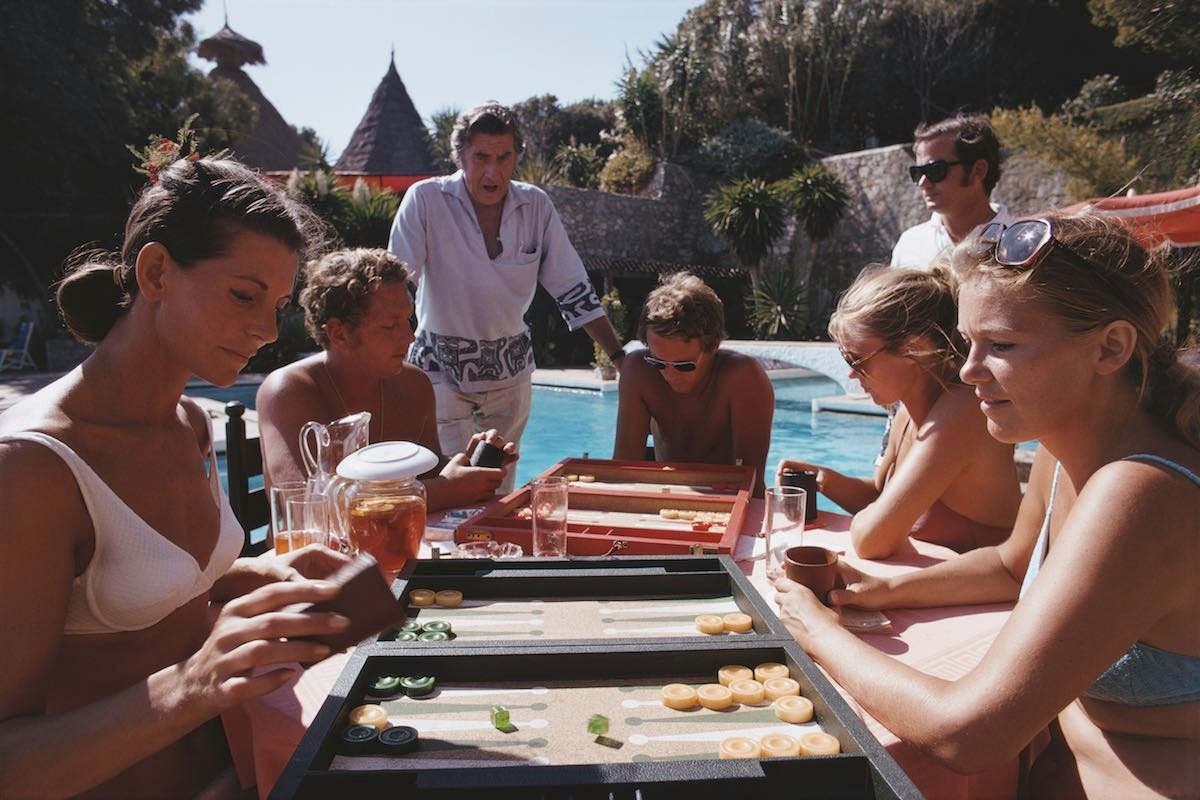 A group of people playing backgammon by a swimming pool at Marbella Beach Club, Spain, September 1970. (Photo by Slim Aarons/Hulton Archive/Getty Images)