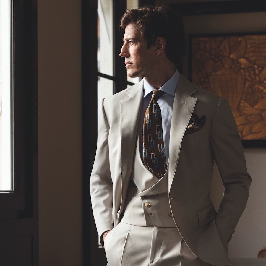 Iconic II: Three-piece beige wool suit; light blue classic shirt; brown silk tie with blue and white rectangles; khaki floral pocket-square.