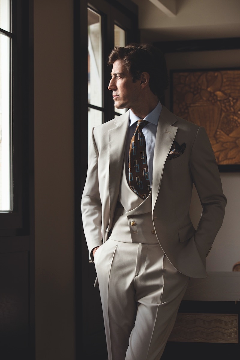 Iconic II: Three-piece beige wool suit; light blue classic shirt; brown silk tie with blue and white rectangles; khaki floral pocket-square.