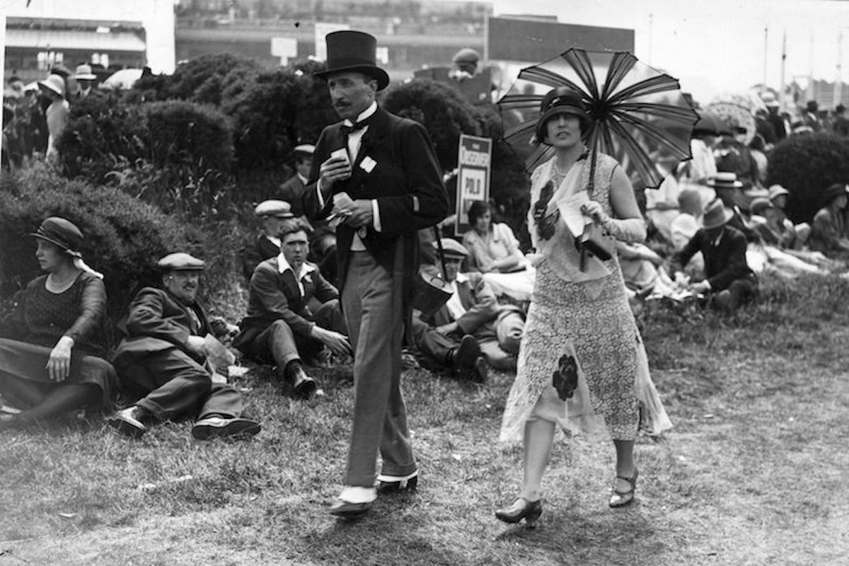 A couple of racegoers at Ascot, the woman in a fashionable dress with a parasol and the man in a morning suit. (Photo by Davis Jr/Topical Press Agency/Getty Images)