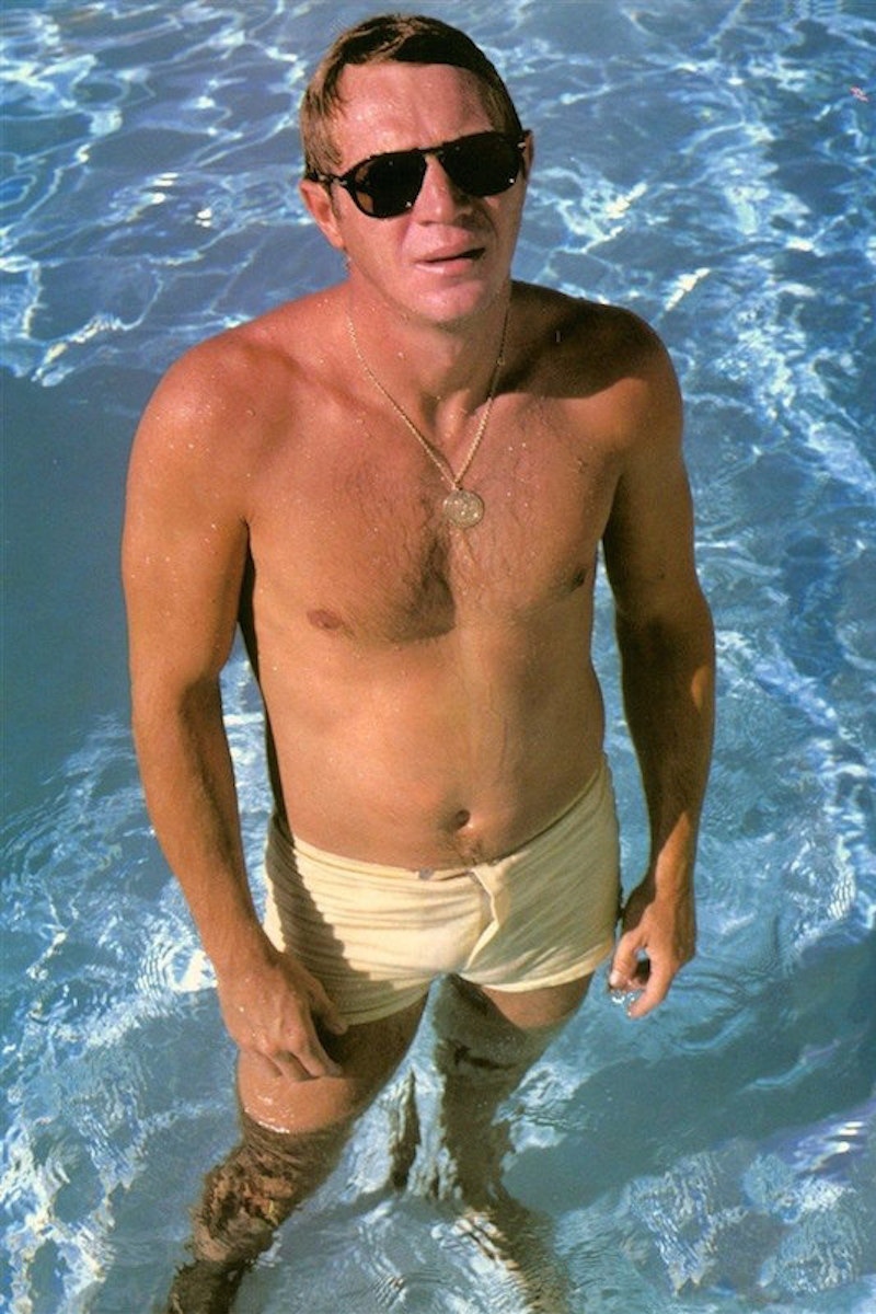 Steve McQueen wearing swim shorts and his signature Persol sunglasses, circa 1960s.