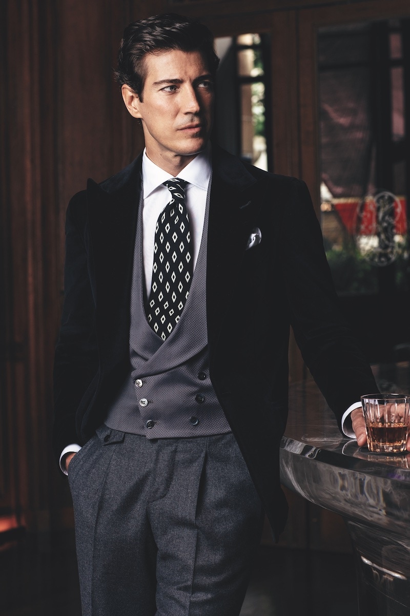 Maxim’s: Black velvet single-breasted dinner jacket; grey flannel trousers and grey textured double-breasted waistcoat made from Super 130 wool and silk; white cotton classic shirt; black with white diamonds silk tie.