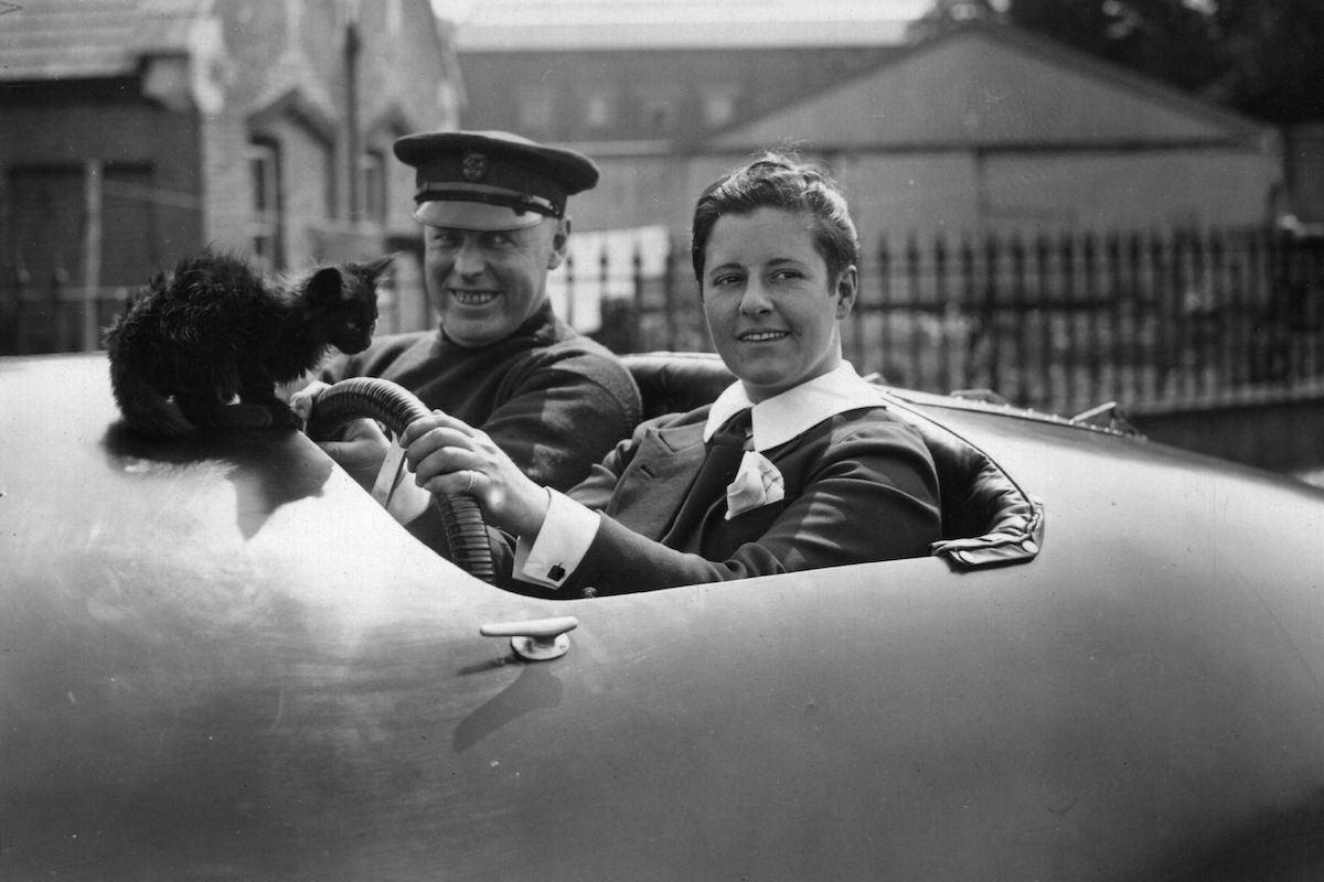 At the wheel of a speedboat with Joe Harris and her pet cat, 1928 (Photo by Topical Press Agency/Getty Images)