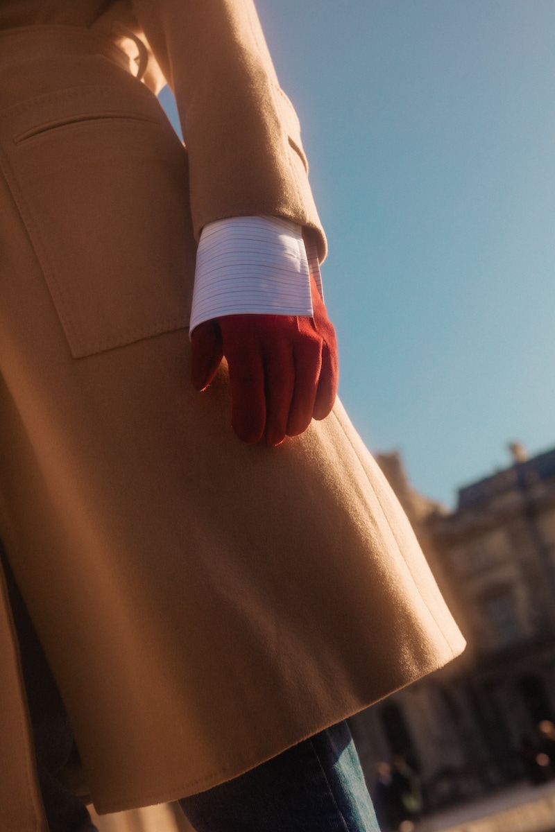 Richard wears: Camel wool Raglan coat, white, red and blue cotton striped pin collar shirt, both Edward Sexton at The Rake; knitted Fair Isle car vest, Connolly; red soft suede leather gloves, Anderson & Sheppard; denim, loafers and tie, models own.