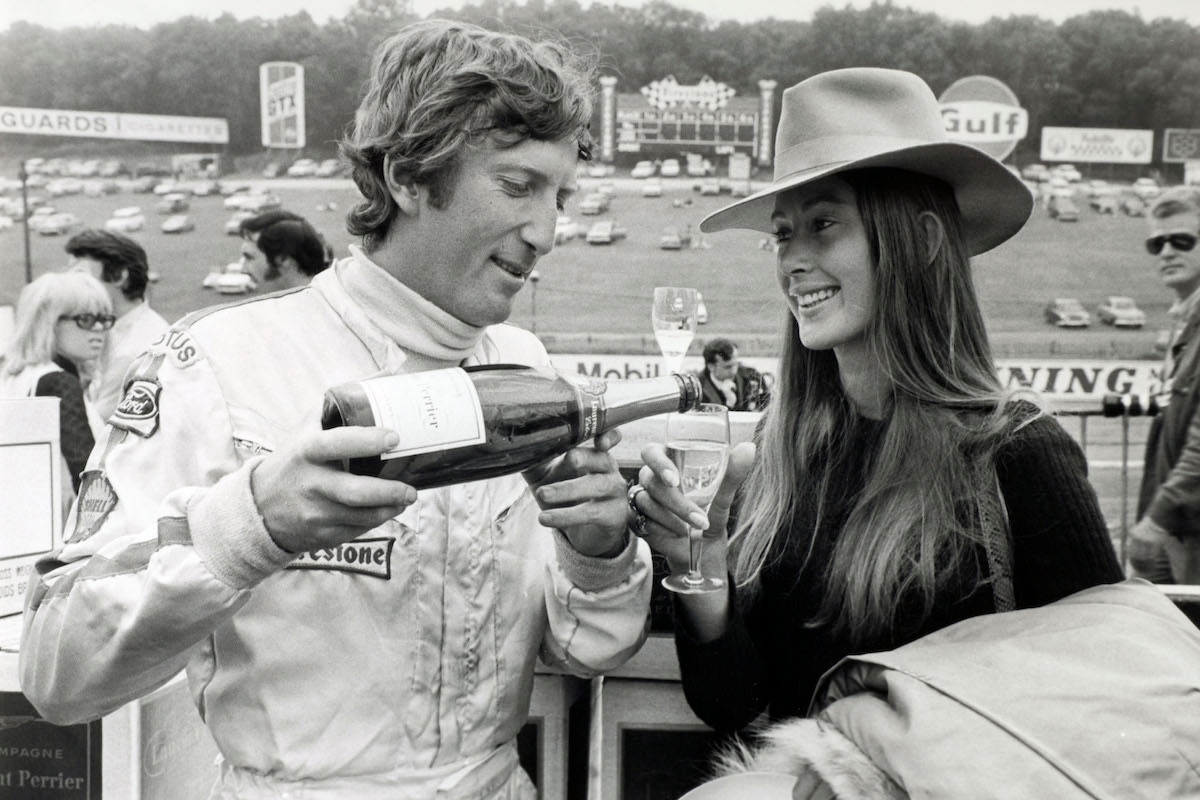 Austria's Jochen Rindt pours a glass of champagne for his wife Nina at the British Grand Prix at Brands Hatch, 1970.